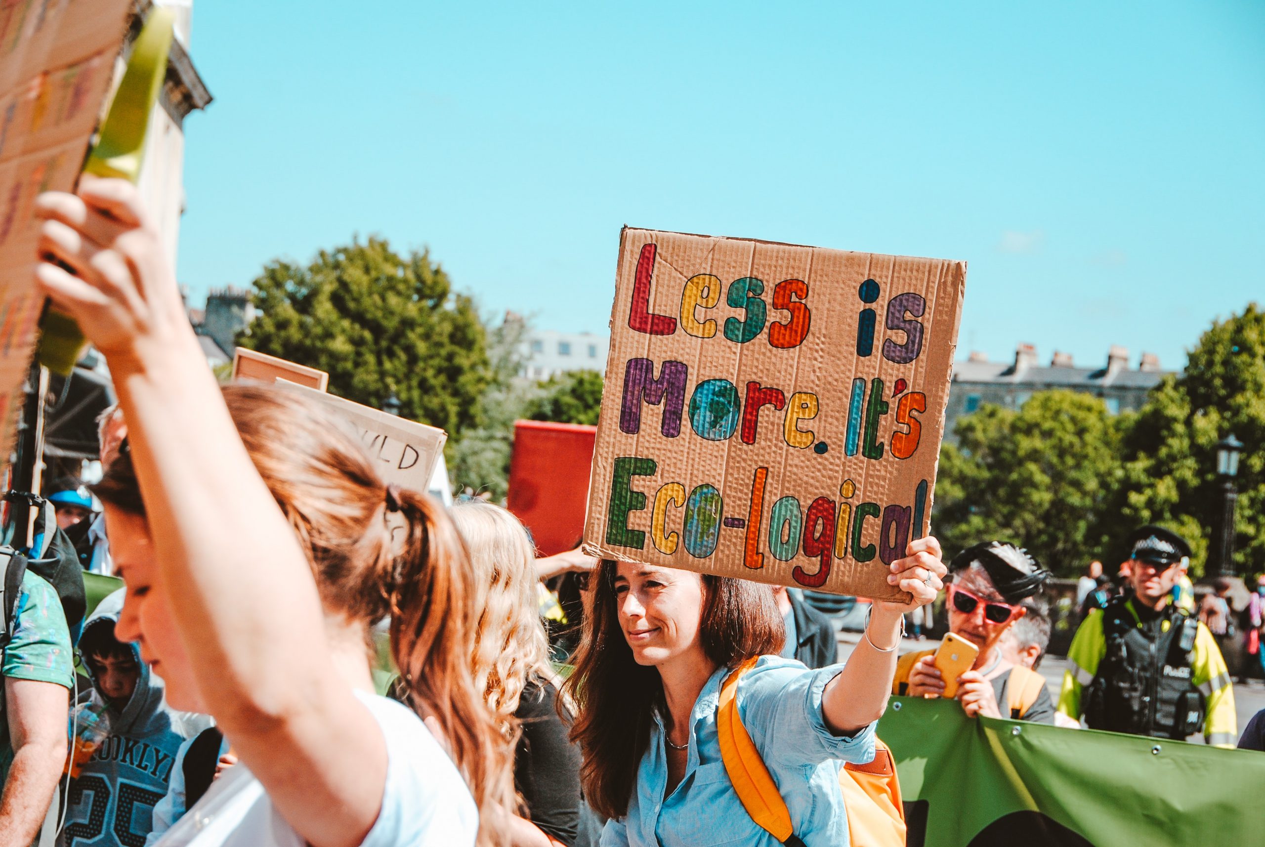 Climate tally with a woman holding up a sign that says less is more. It's eco-logical.